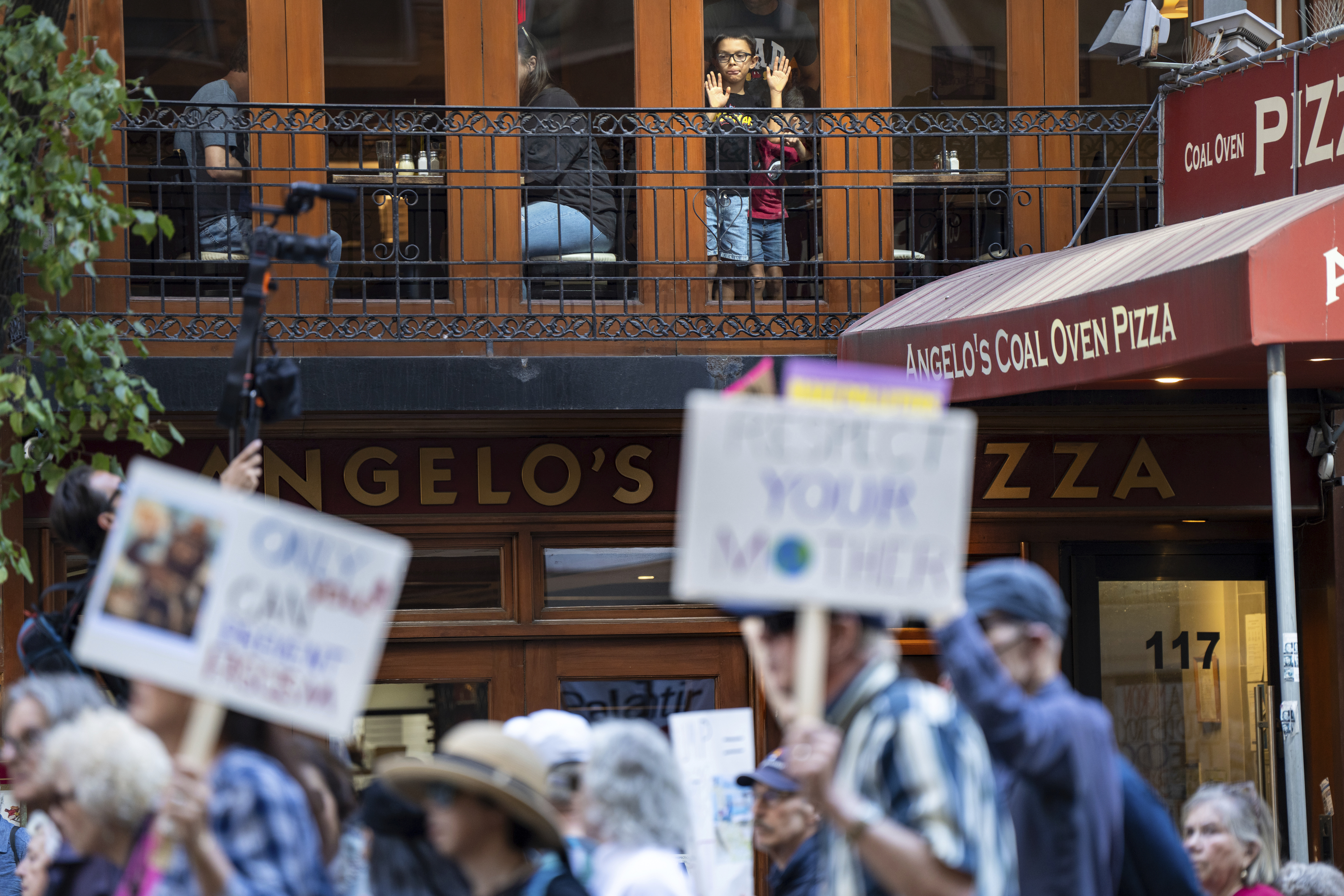 Children watch from inside a restaurant as people march through Manhattan in the 