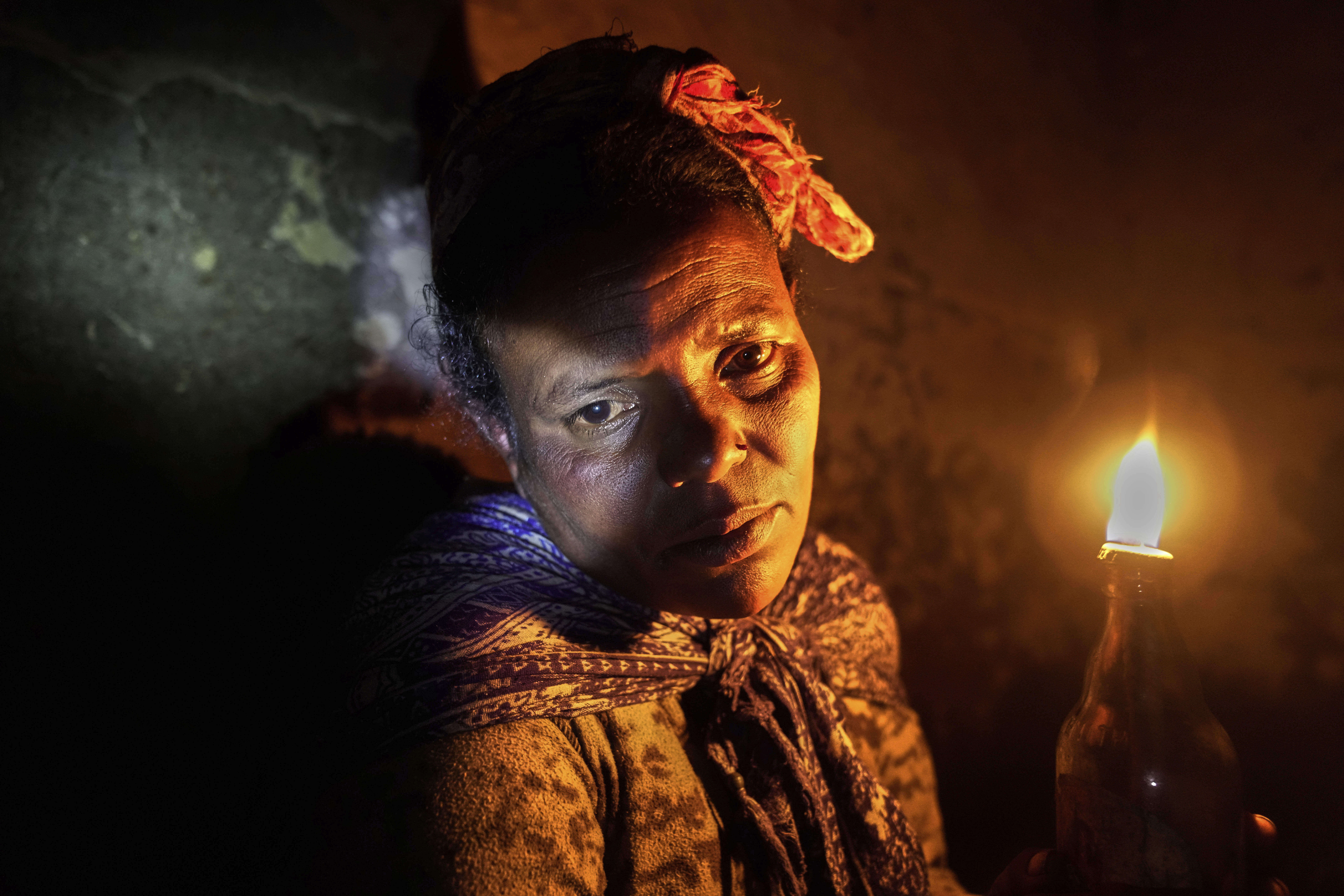 Fanuse Adete, 38 years-old, holds up a candle she uses to light her home at night in the Menabichu district on the outskirts of Addis Ababa, Ethiopia, Saturday, Sept. 6, 2025. (Brian Inganga - AP)