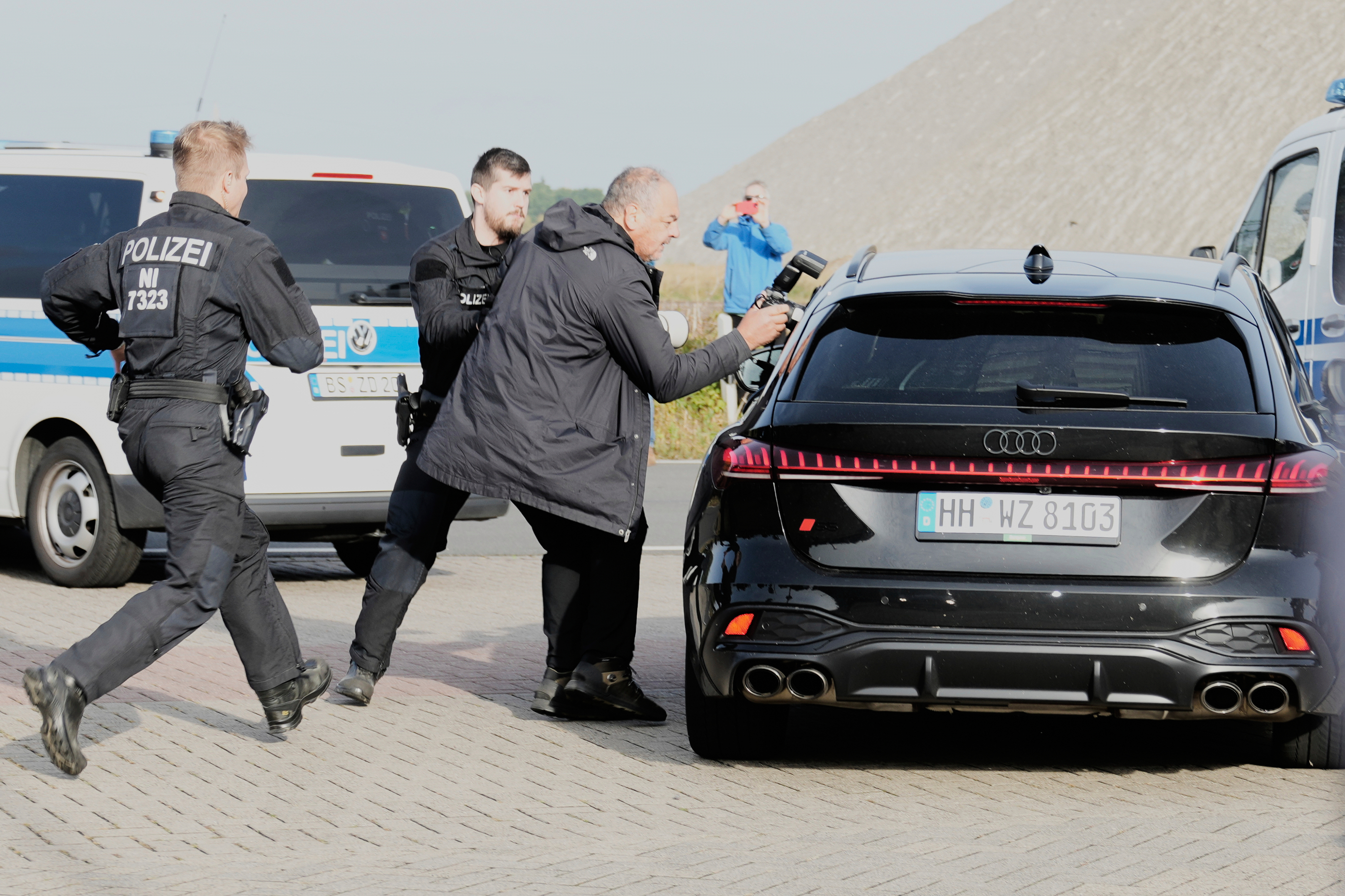 Police officers try to stop a British photographer as he takes pictures inside a car leaving a prison, carrying Christian B., a suspect in the 2007 disappearance of British toddler Madeleine McCann, in Sehnde, Germany, Wednesday, Sept. 17, 2025. (Markus Schreiber - AP)