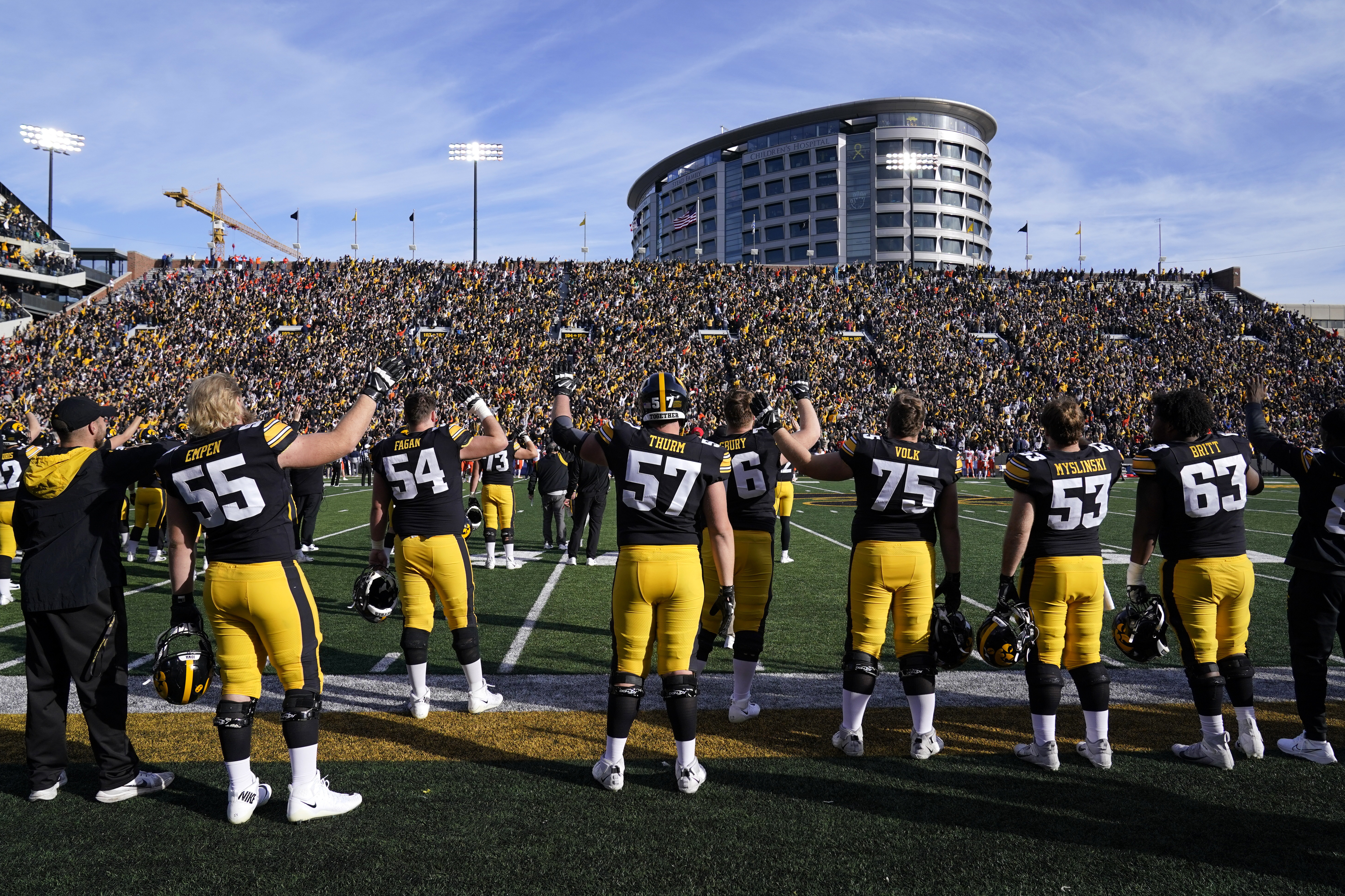 FILE - Iowa players wave to children in the University of Iowa Stead Family Children's Hospital, building in background, at the end of the first quarter of an NCAA college football game against Illinois, Saturday, Nov. 20, 2021, in Iowa City, Iowa. (Charlie Neibergall - AP)
