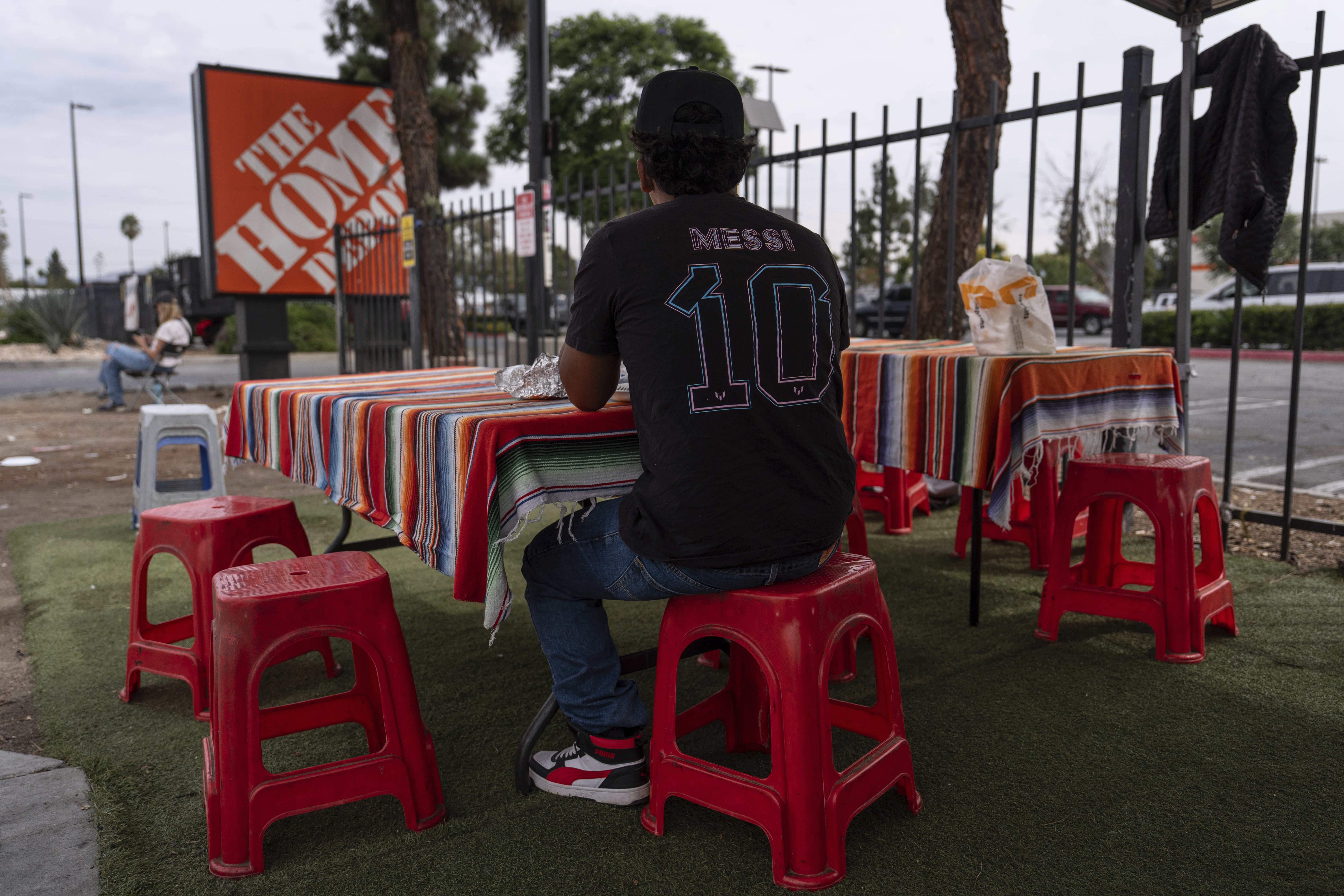 A day laborer eats his meal near a Home Depot sign in the Van Nuys section of Los Angeles, Thursday, Aug. 28, 2025. (Jae C. Hong - AP)