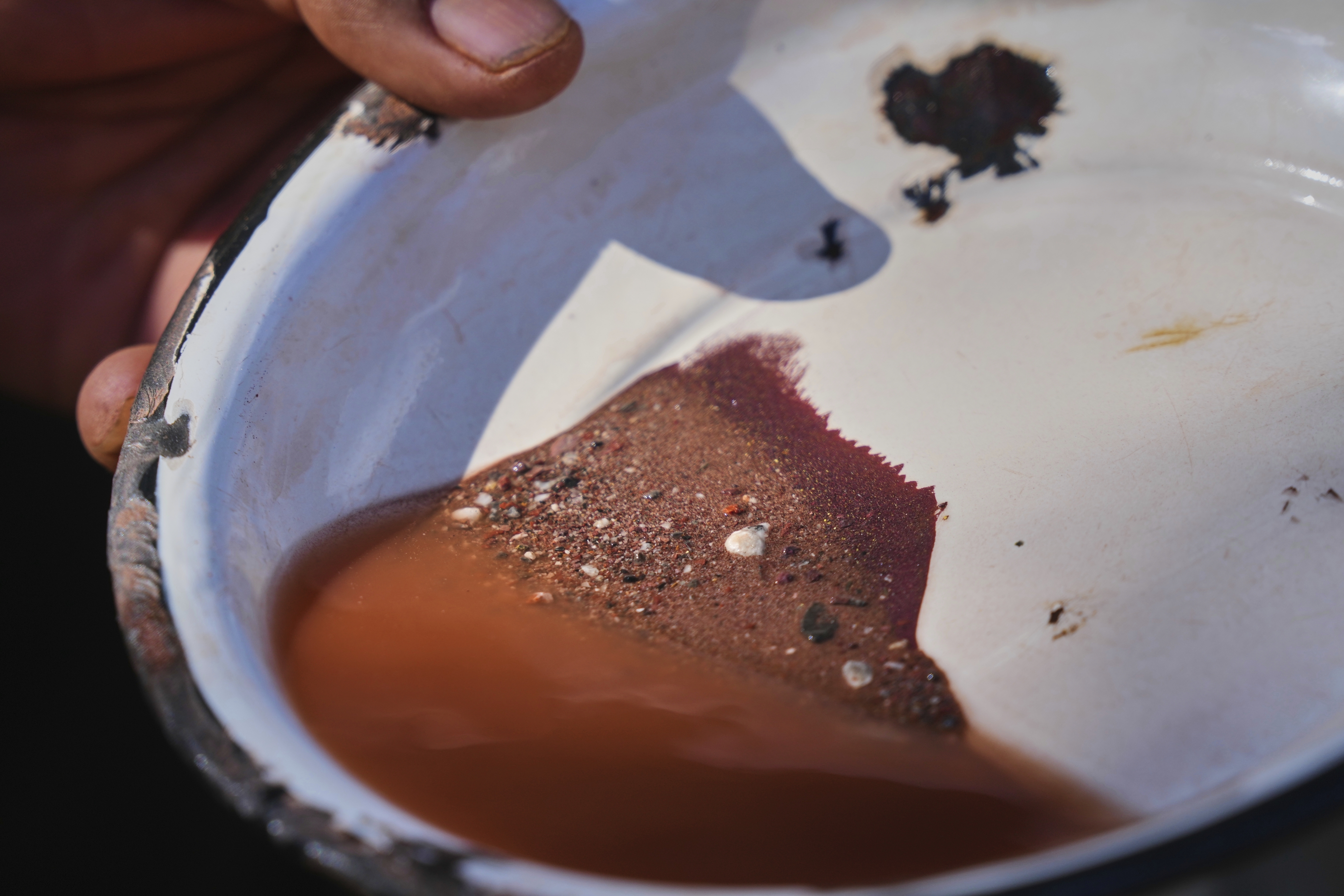 Hugo Flores looks at some samples of mercury ore, at the top, to calculate the cooking time in the furnace in San Joaquin, Mexico, Tuesday, Aug. 19, 2025. (Fernando Llano - AP)