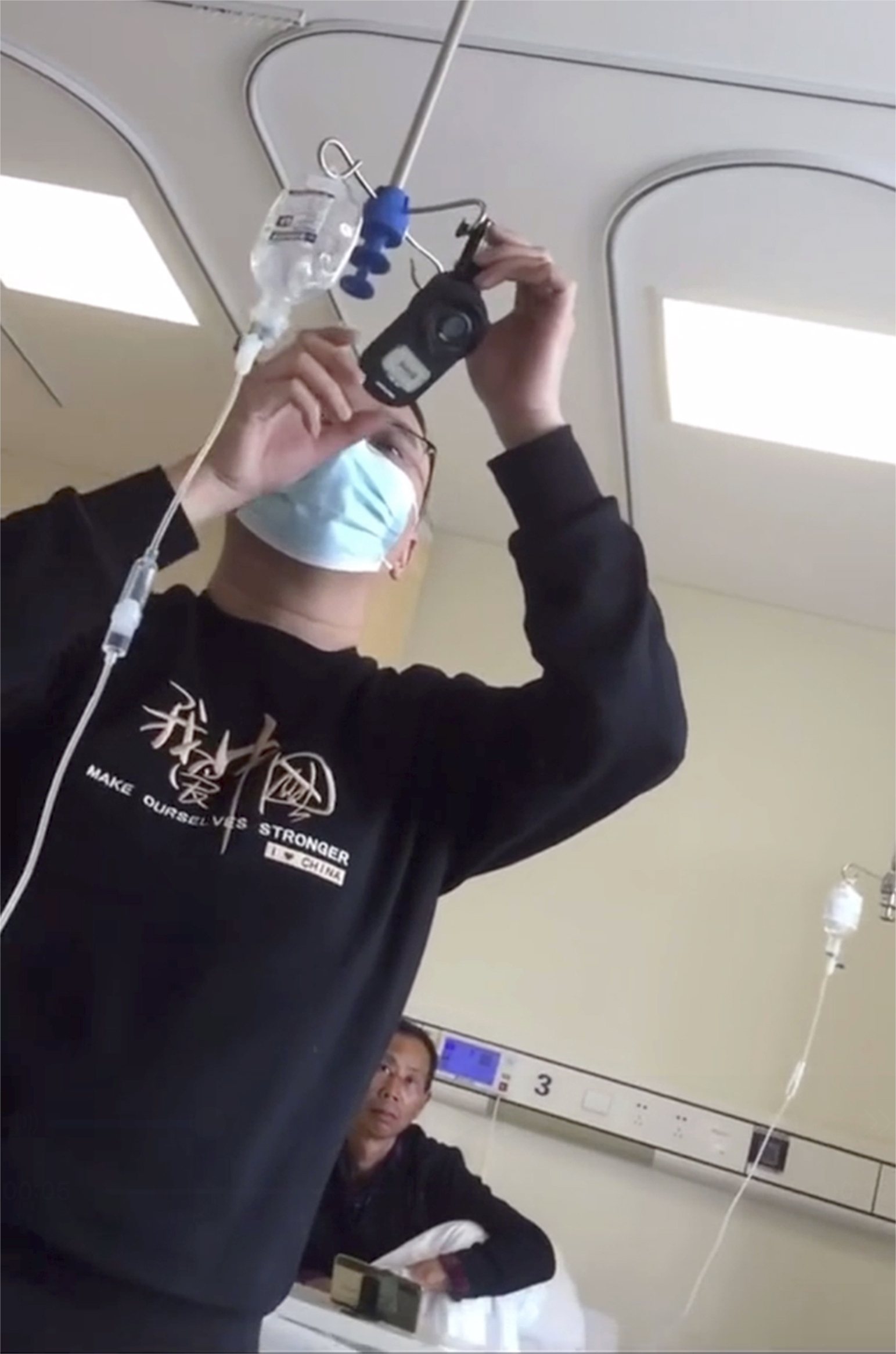 In this screen grab image from video, a police officer hangs a body camera from an IV drip to monitor Yang Guoliang as he lays in a hospital bed after police beat him with bricks, Tuesday, March 12, 2024, in Changzhou in eastern China's Jiangsu Province. (Yang Family - Yang Family)