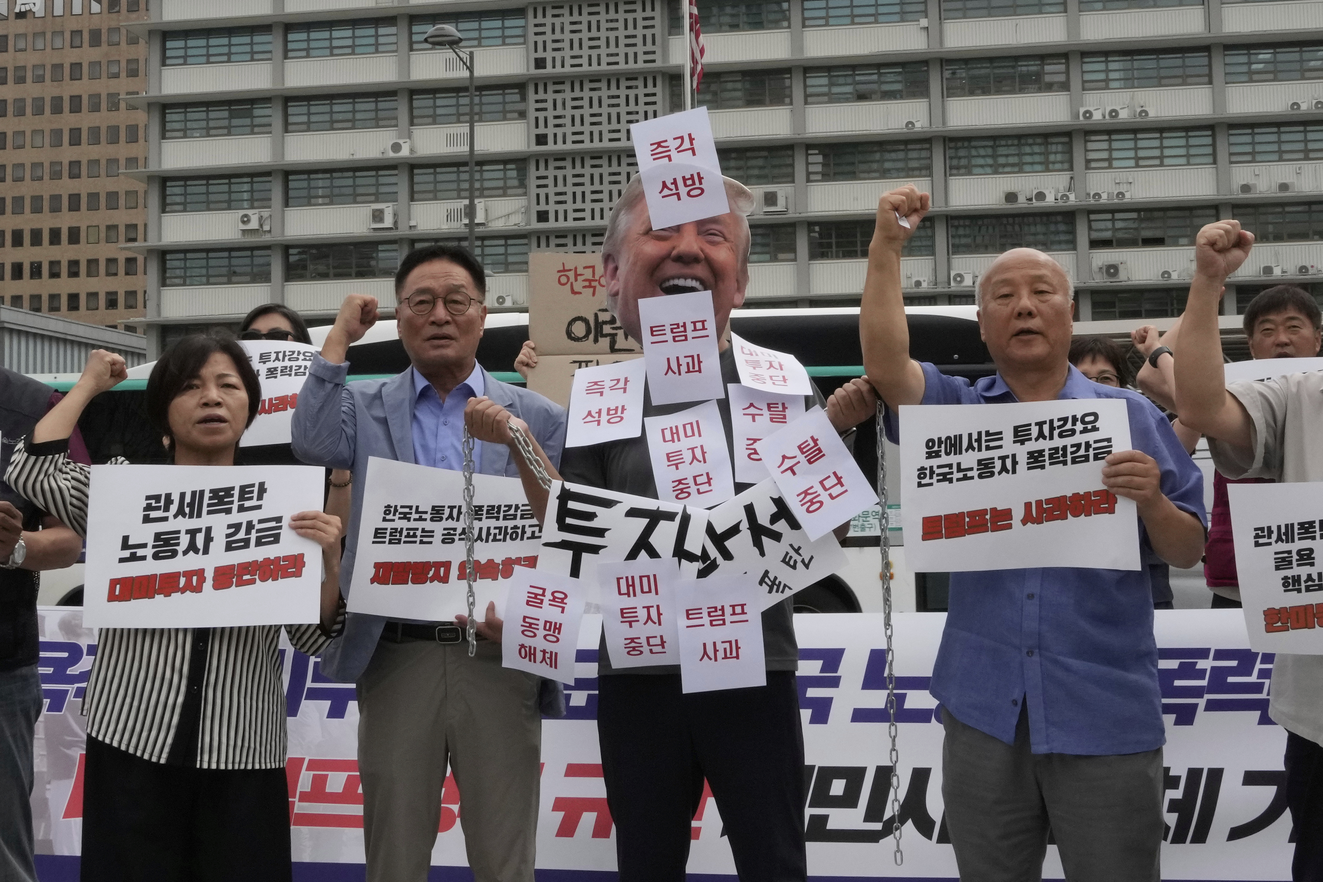 A protester wearing a mask of U.S. President Donald Trump attends a rally against the detention of South Korean workers during an immigration raid in Georgia, near the U.S. Embassy in Seoul, South Korea, Tuesday, Sept. 9, 2025. The part of letters read 