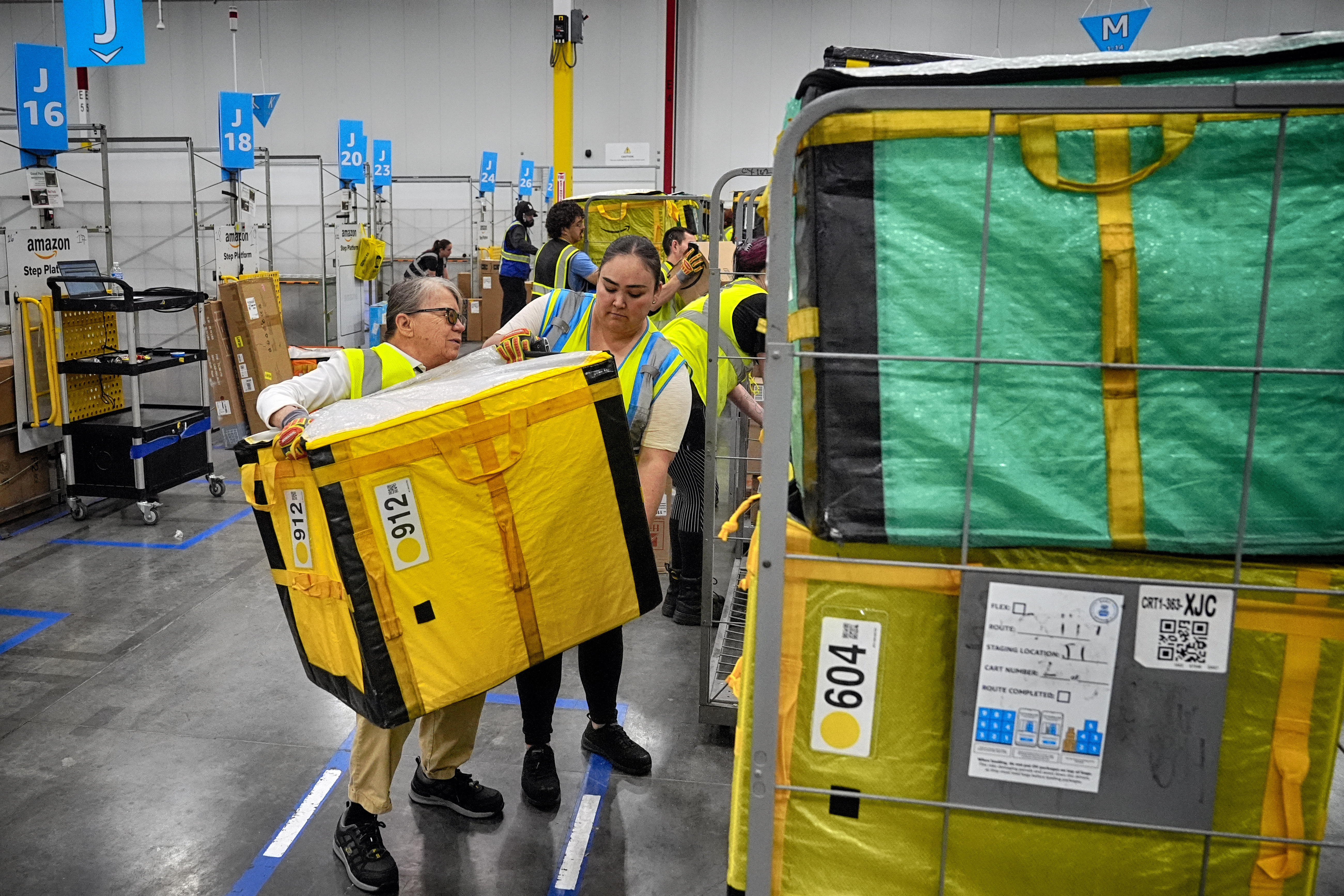 Amazon employees load packages on carts before being put on to trucks for distribution customers for Amazon's annual Prime Day event at an Amazon's DAX7 delivery station on July 16, 2024, in South Gate, Calif. (Richard Vogel - AP)