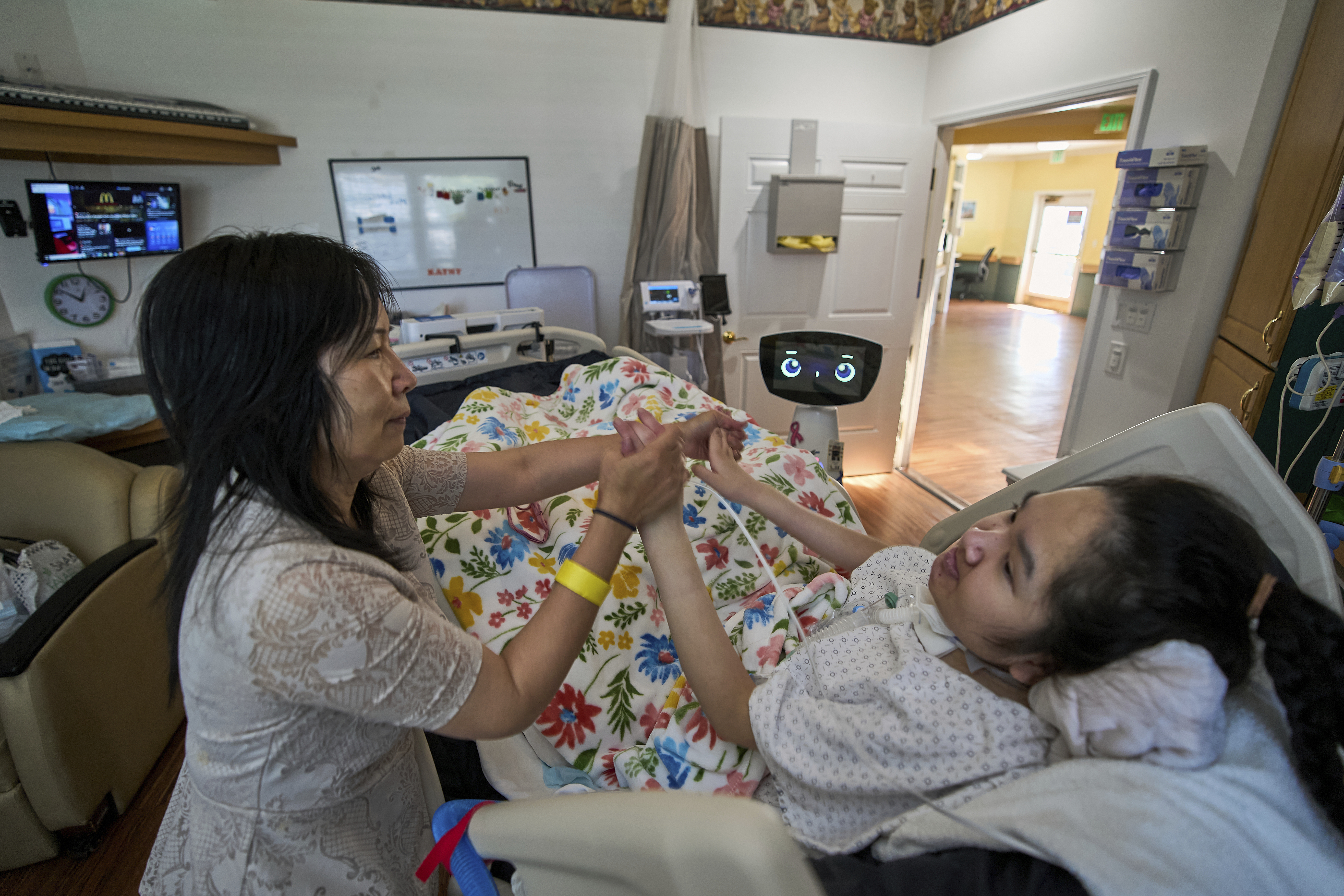 Cara Nguyen with her daughter, Kathy, 18, are visited by Robin the Robot at the HealthBridge Orange Specialty Pediatric Hospital in Orange, Calif., on Friday, Sept. 12, 2025. (Damian Dovarganes - AP)