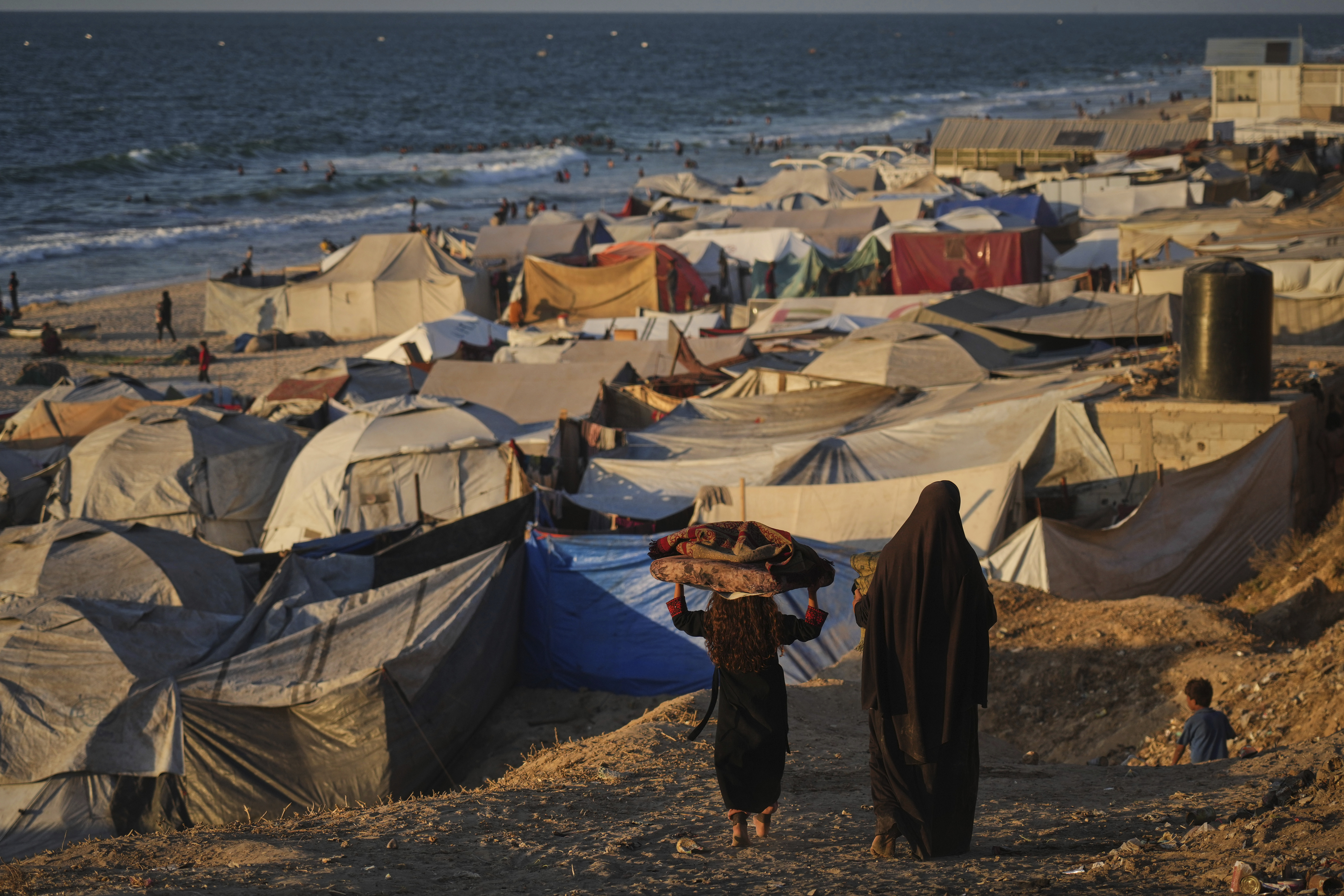 Displaced Palestinians walk through a makeshift tent camp along the shore of Deir al-Balah in the Gaza Strip Tuesday, Sept. 16, 2025. (Jehad Alshrafi - AP)