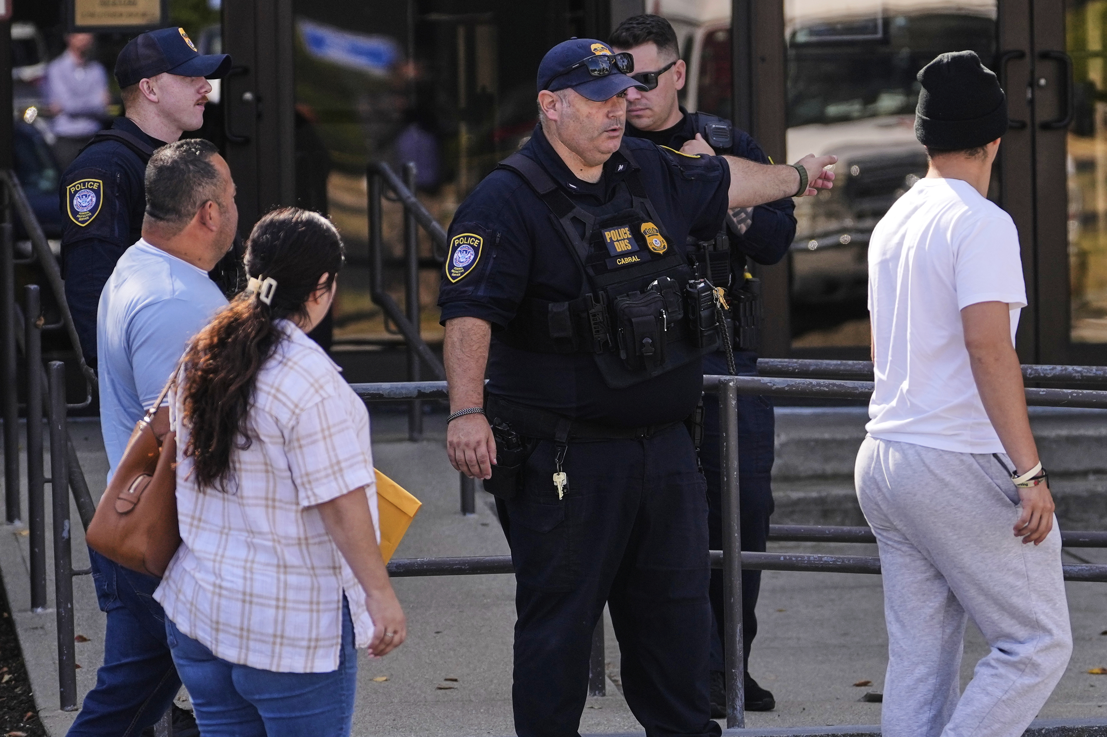A Department of Homeland Security police officer directs visitors towards the front door of the U.S. Immigration and Customs Enforcement regional field office, Tuesday, Sept. 16, 2025, in Burlington, Mass. (Charles Krupa - AP)