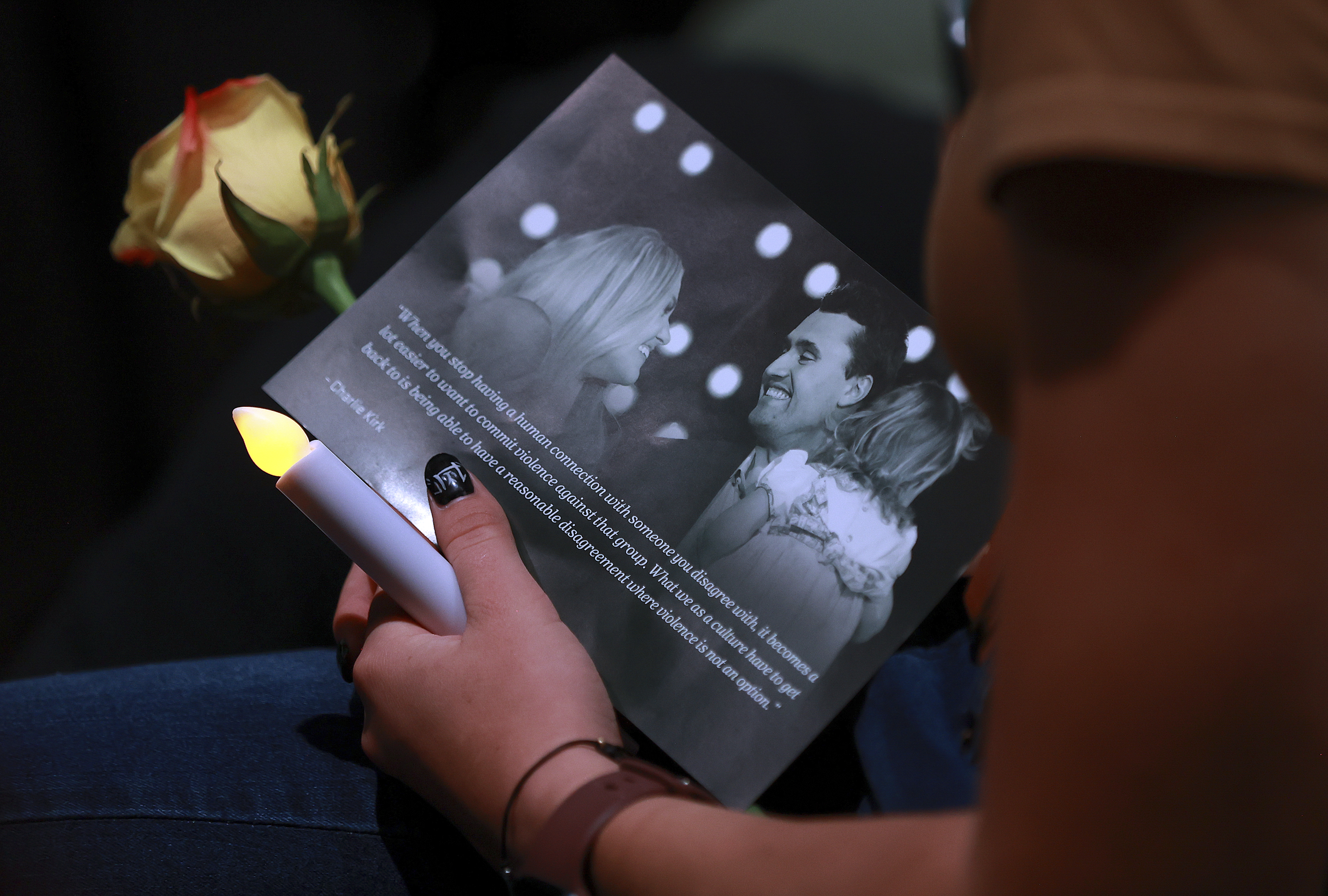 A woman holds a candle, flower and flyer during a Vigil for Unity at the UCCU Center at Utah Valley University in Orem on Friday, Sept. 19, 2025. Charlie Kirk, conservative activist and the founder and president of Turning Point USA, was fatally shot while answering questions at his American Comeback Tour at UVU on Sept. 10. (Kristin Murphy - The Deseret News)