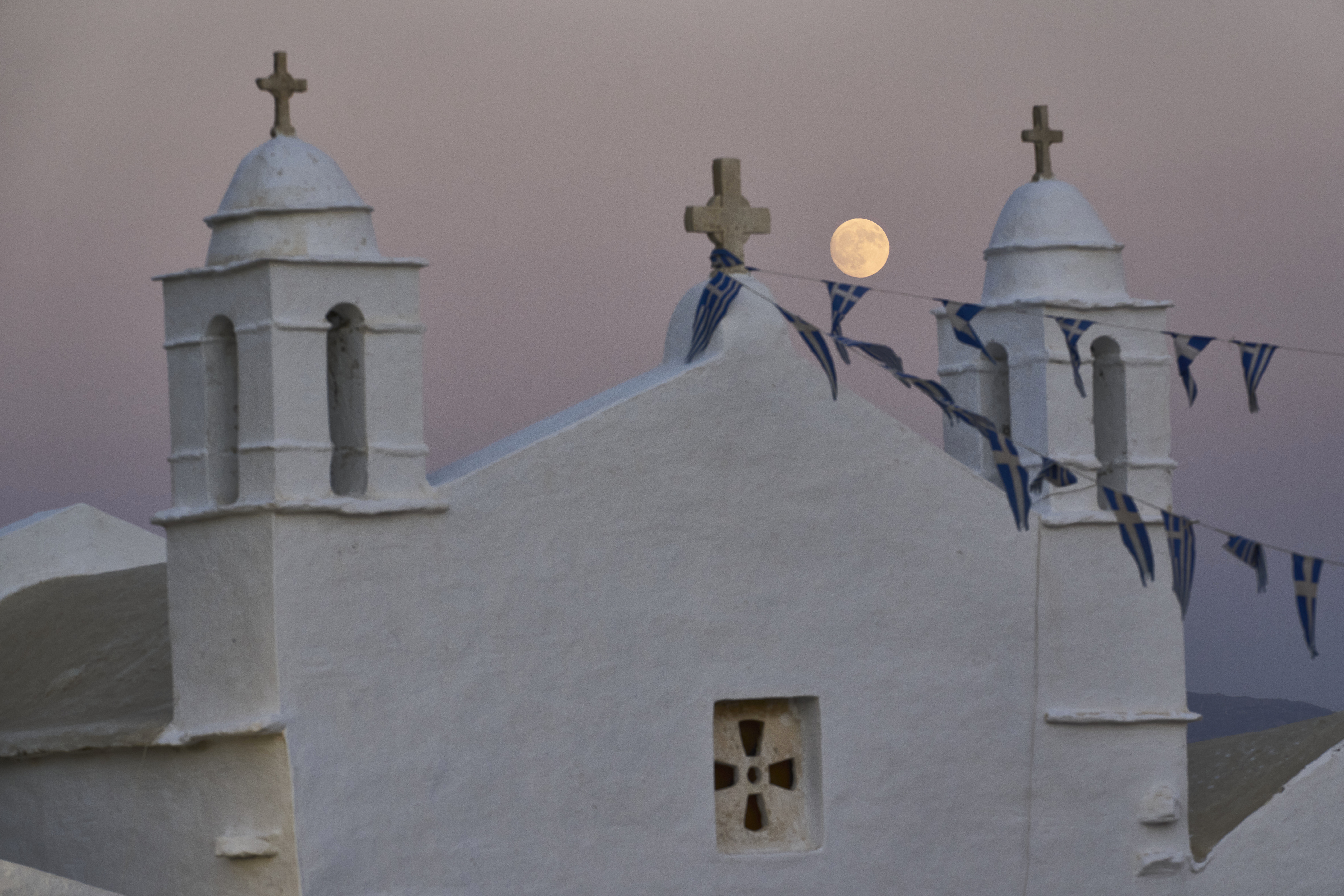 The moon rises behind the family-owned Agios Sostis chapel during its panigiri day on the island of Tinos, Greece, Saturday, Sept. 6, 2025. (Petros Giannakouris - AP)