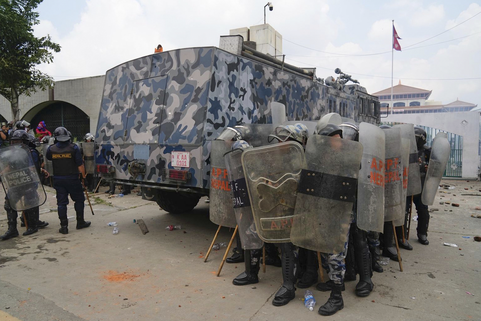 Riot police take cover behind an armored vehicle during clashes with protesters outside the Parliament building in Kathmandu, Nepal, Monday, Sept. 8, 2025. (Niranjan Shrestha - AP)