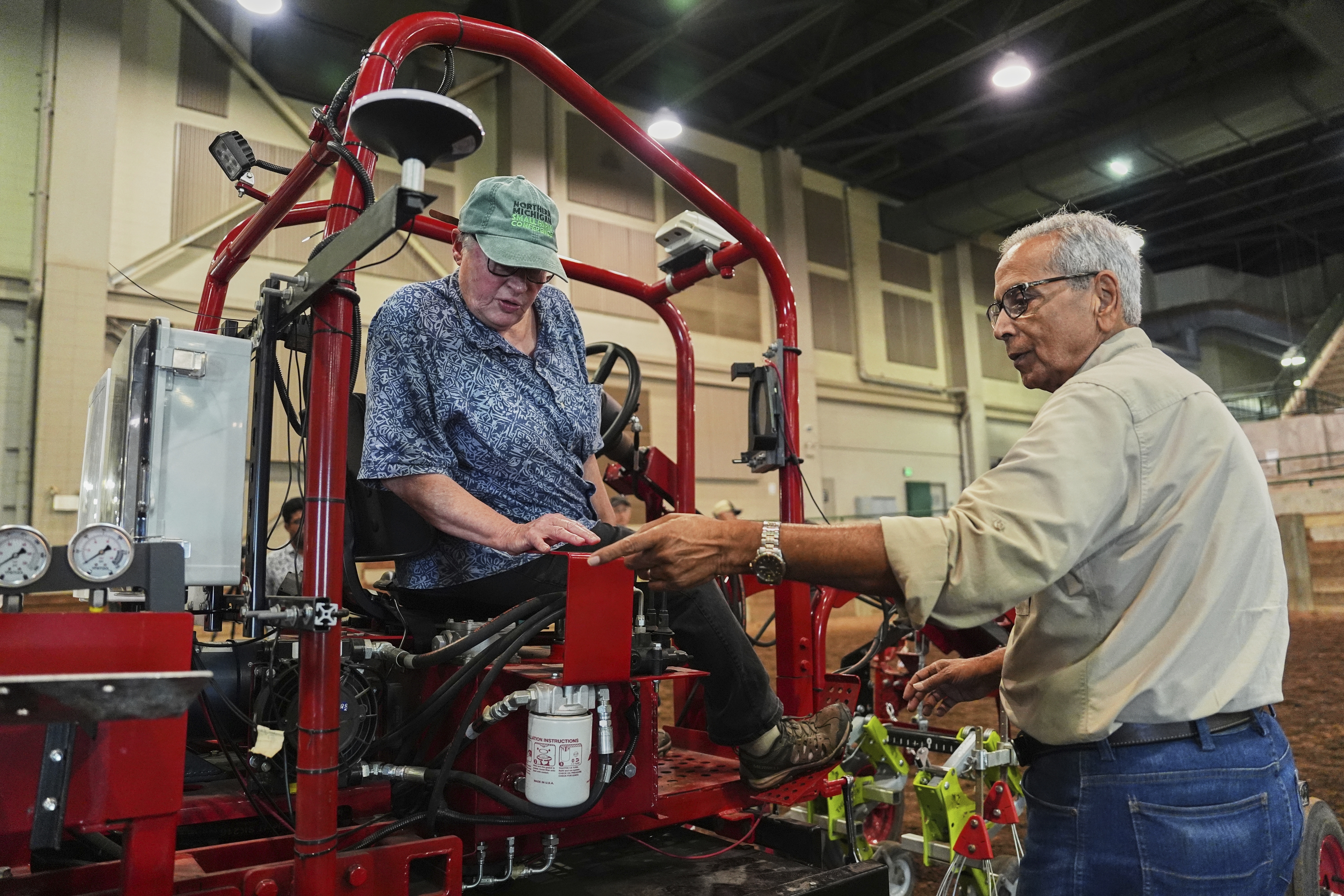 Farmer Vicki Morrane, left, listens as Ajit Srivastava, right, explains the mechanics of an electric tractor before she test drives Tuesday, Aug. 19, 2025, in East Lansing, Mich. (Joshua A. Bickel - AP)
