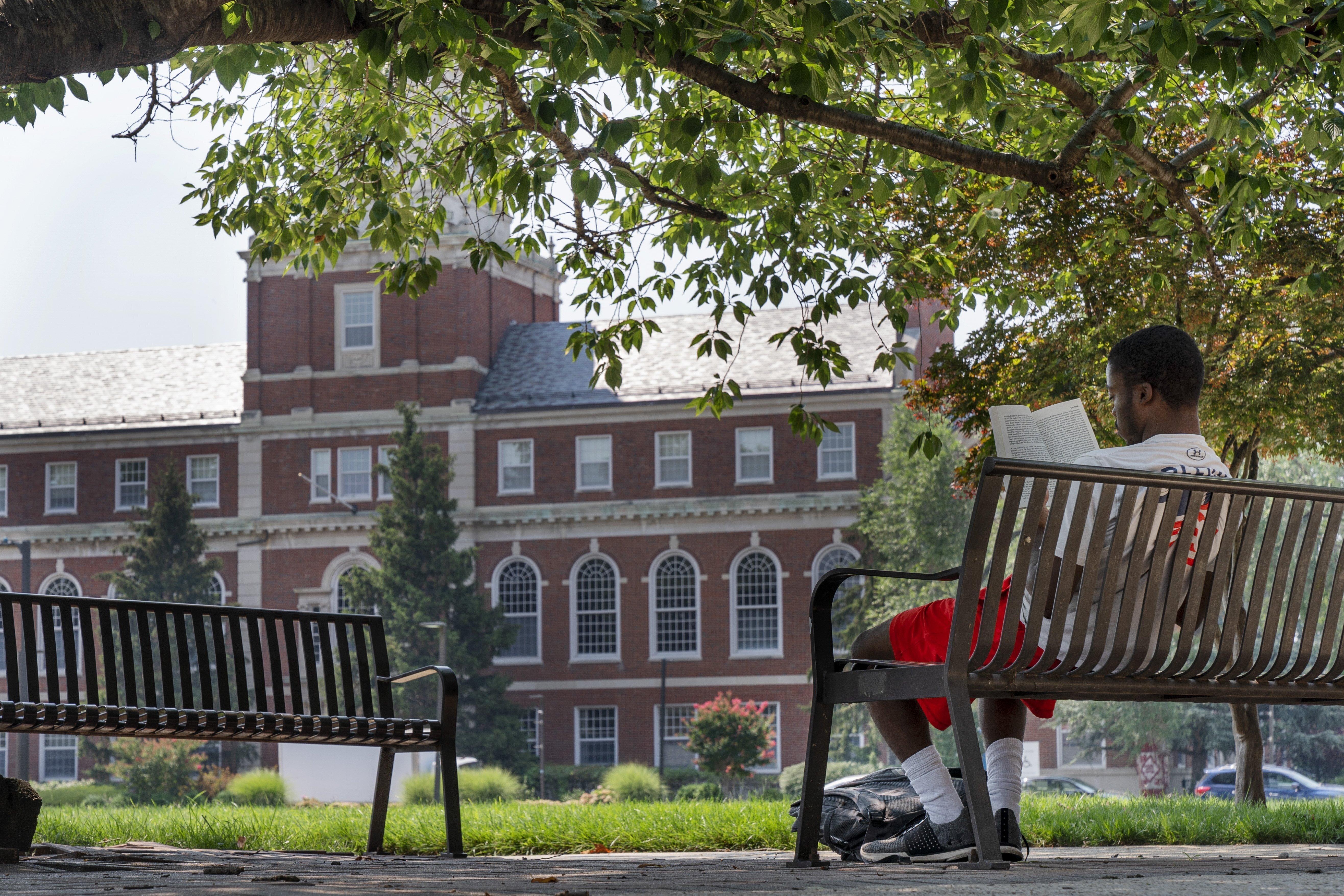 FILE - With the Founders Library in the background, a young man reads on Howard University campus July 6, 2021, in Washington. (Jacquelyn Martin - AP)