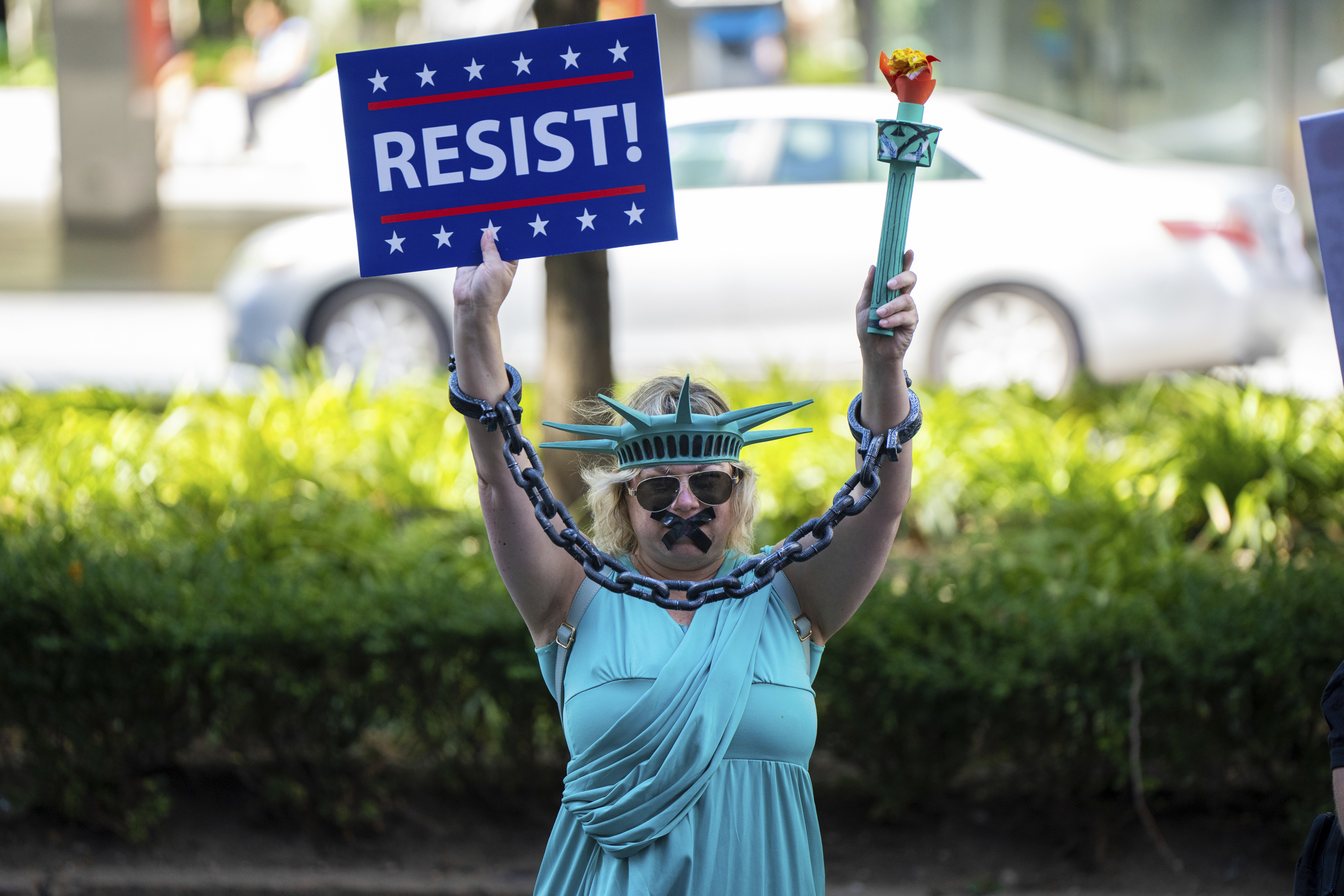 A woman dressed as the Statue of Liberty in chains protests at the 
