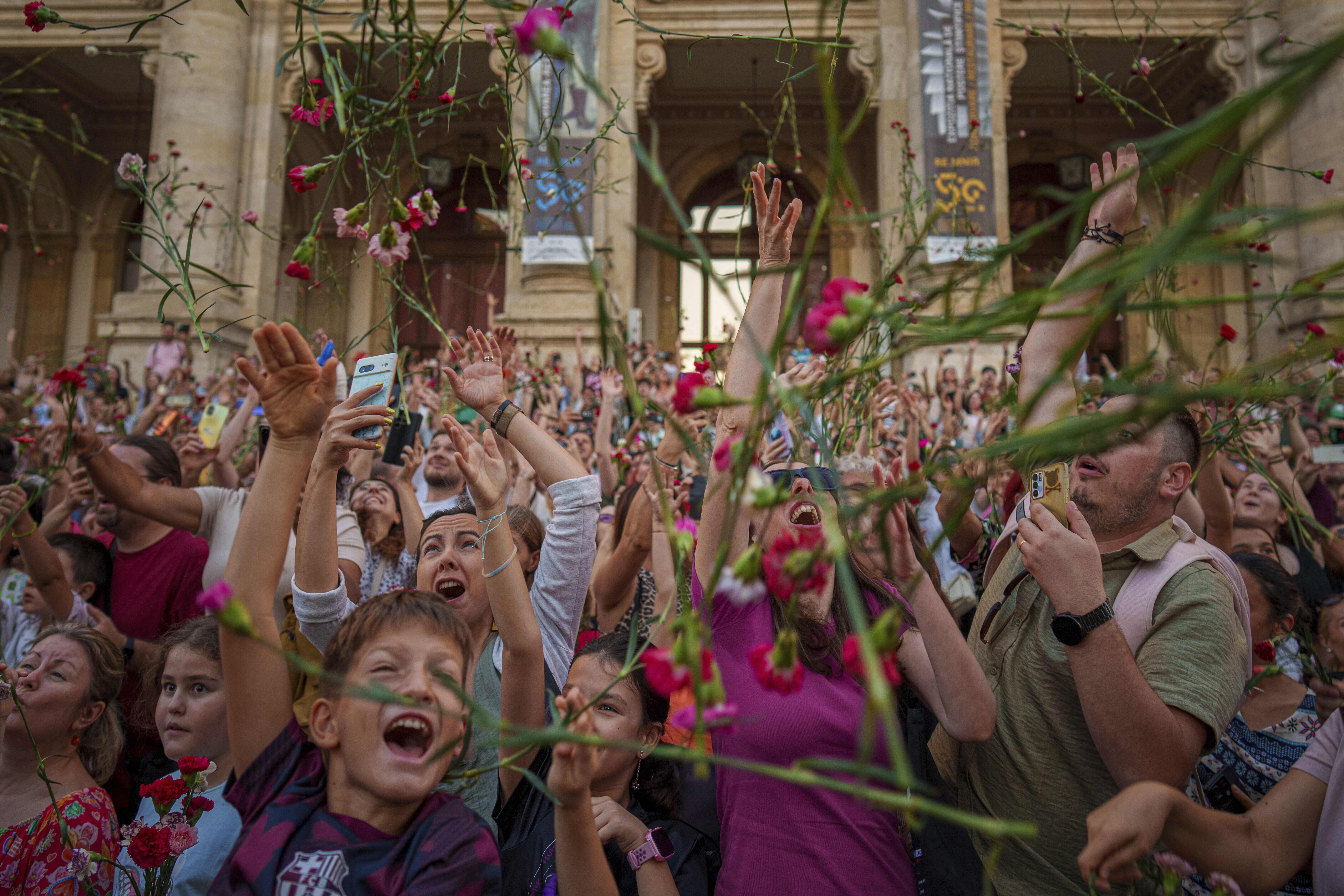 People throw carnations during an event marking the day when the Romanian capital was first mentioned in historical records, 566 years ago, in Bucharest, Romania, Saturday, Sept. 20, 2025. (Vadim Ghirda - AP)