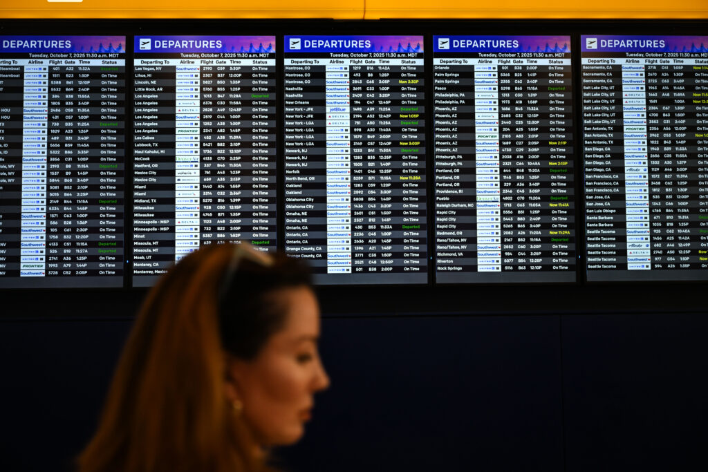 a woman walks by an airport schedule board