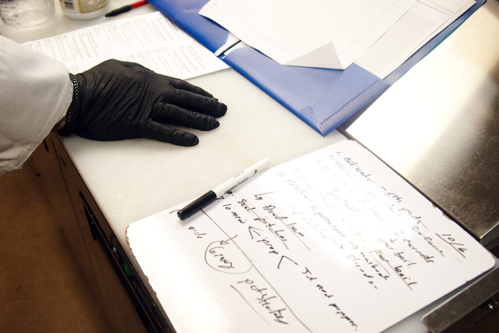 a gloved chef's hand on a notebook