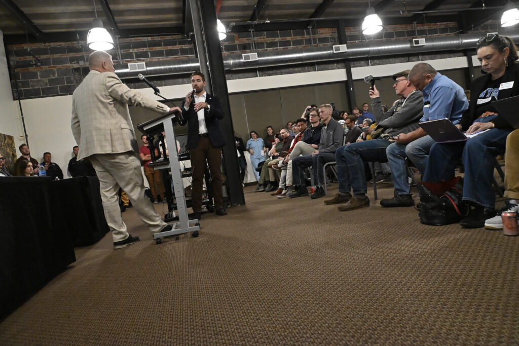 Two men talking in front of an audience