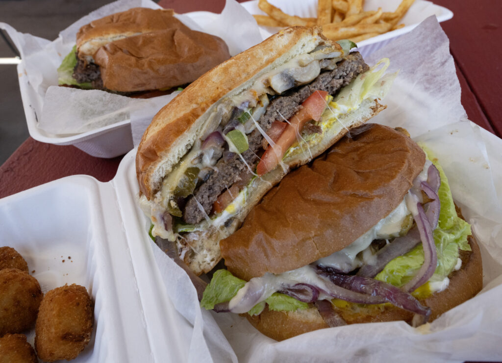 The Wild Burger with sauteed mushrooms, onions, green and jalapeno peppers, and swiss cheese, tomatoes and lettuce at Big burger World on Wednesday, Oct. 29, 2025, in Canon City. On the left is an order of spicy cheese tots. (The Gazette, Christian Murdock)