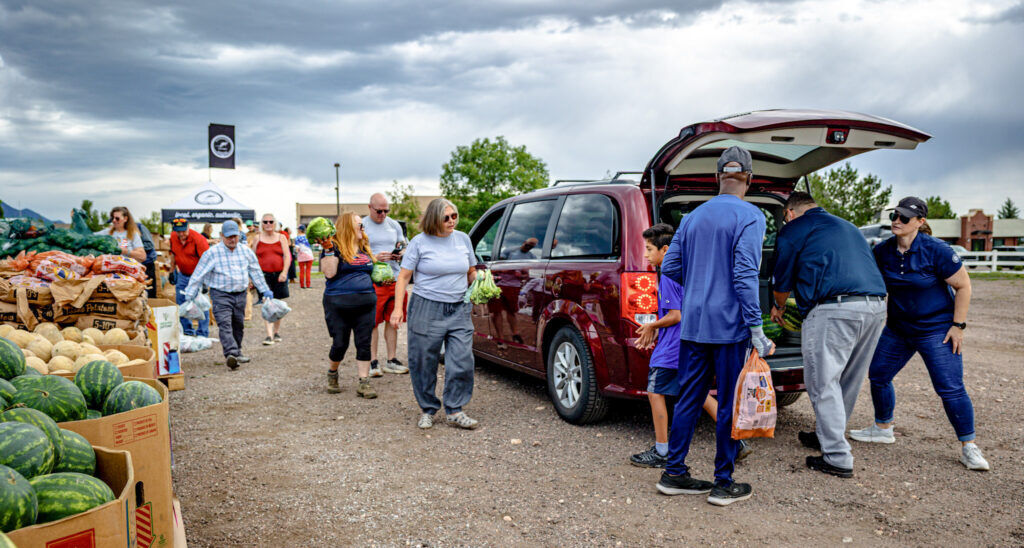 People fill a red van with food.