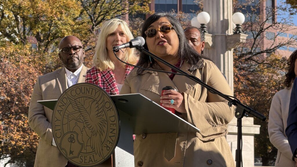 a woman in a coat holding a cup of coffee at an outdoor podium