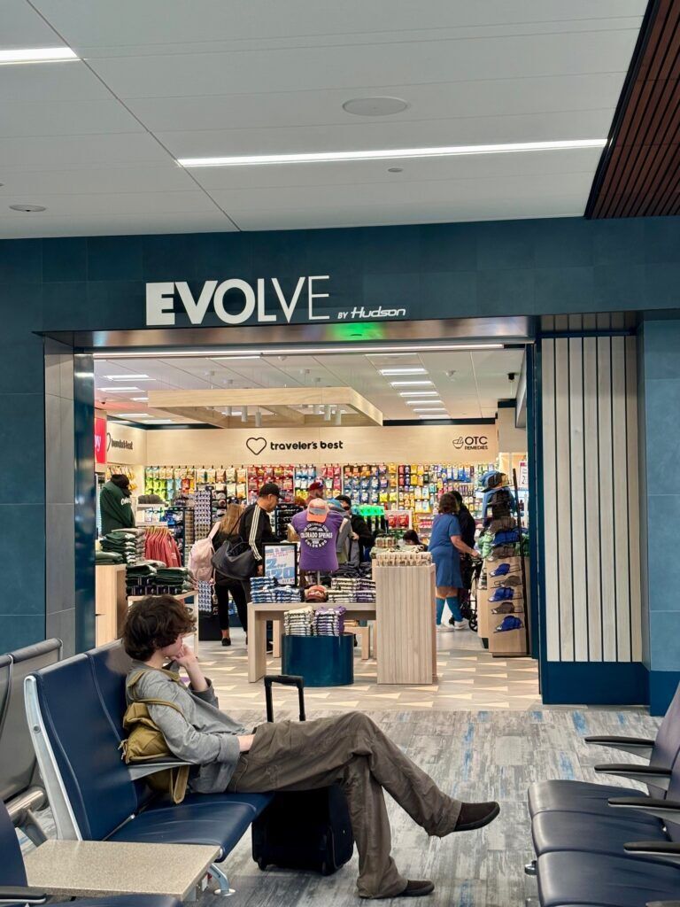 A passenger sits in front of the Evolve by Hudson terminal retail store at Colorado Springs Airport the weekend before Thanksgiving 2025.
