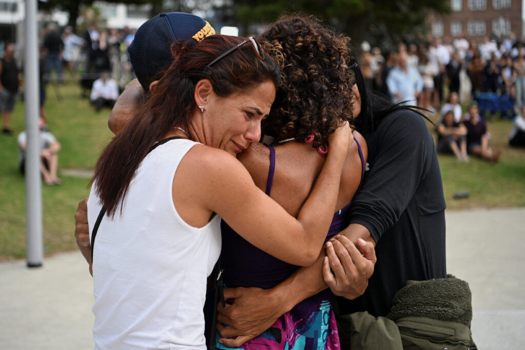 People embrace as they visit a makeshift memorial following the attack on a Jewish holiday celebration at Sydney's Bondi Beach, in Sydney, Australia, December 15, 2025. REUTERS/Flavio Brancaleone