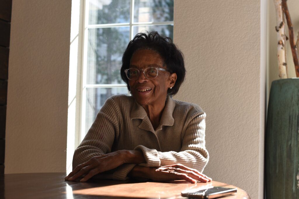 A portrait of a woman sitting at a round wooden table