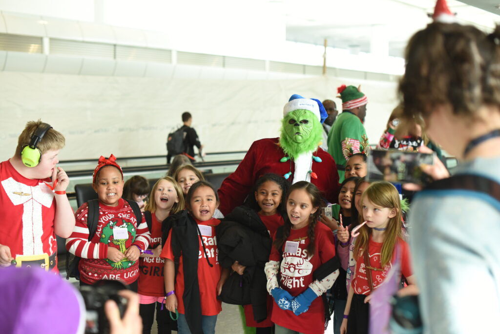 A group of girls pose with someone costumed as The Grinch
