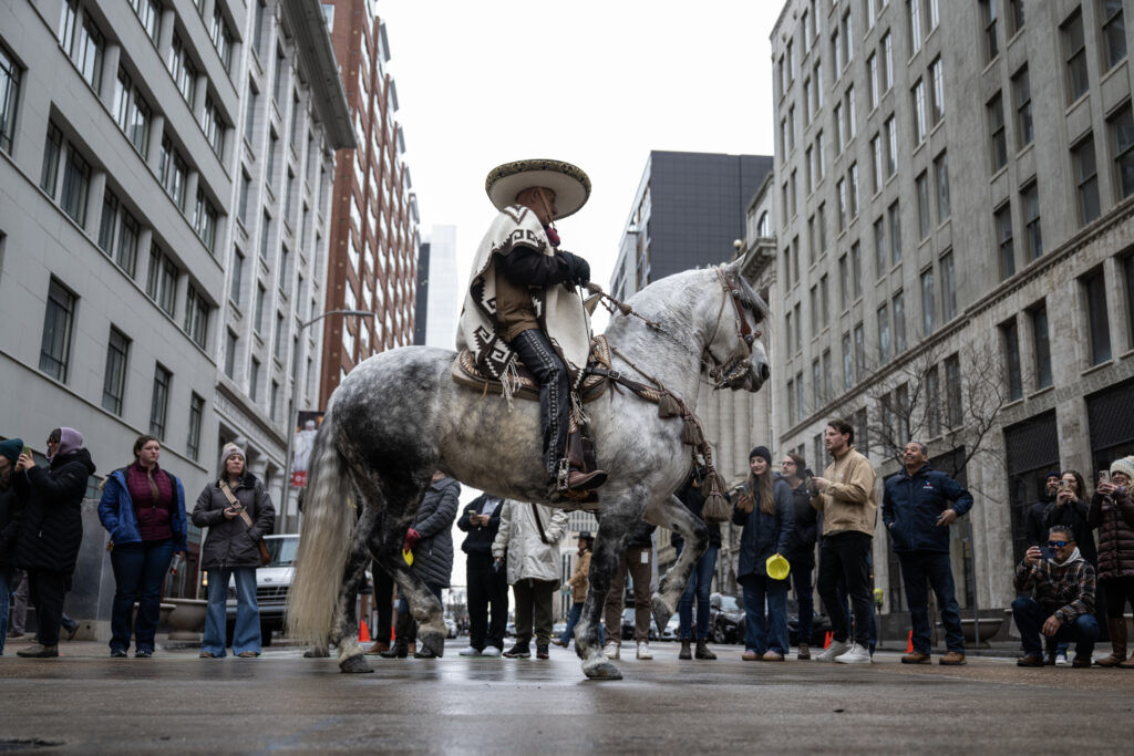 A man in a sombrero stands stationary in a city street