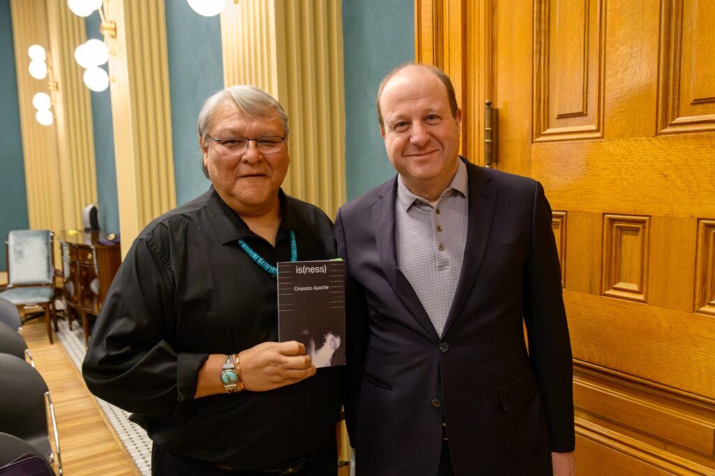 Crisosto Apache holds o book of his poems just after Gov. Jared Polis named them the state's 11th Colorado Poet Laureate. (Photo provided by Governor's office)