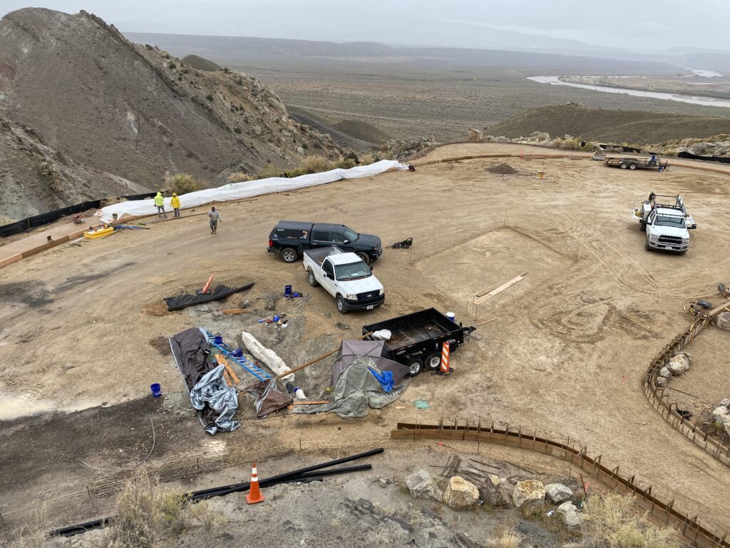View of the parking lot construction at Dinosaur National Monument, with the quarry and fossils exposed near the trucks and trailer. Photo by Rudy Hummel