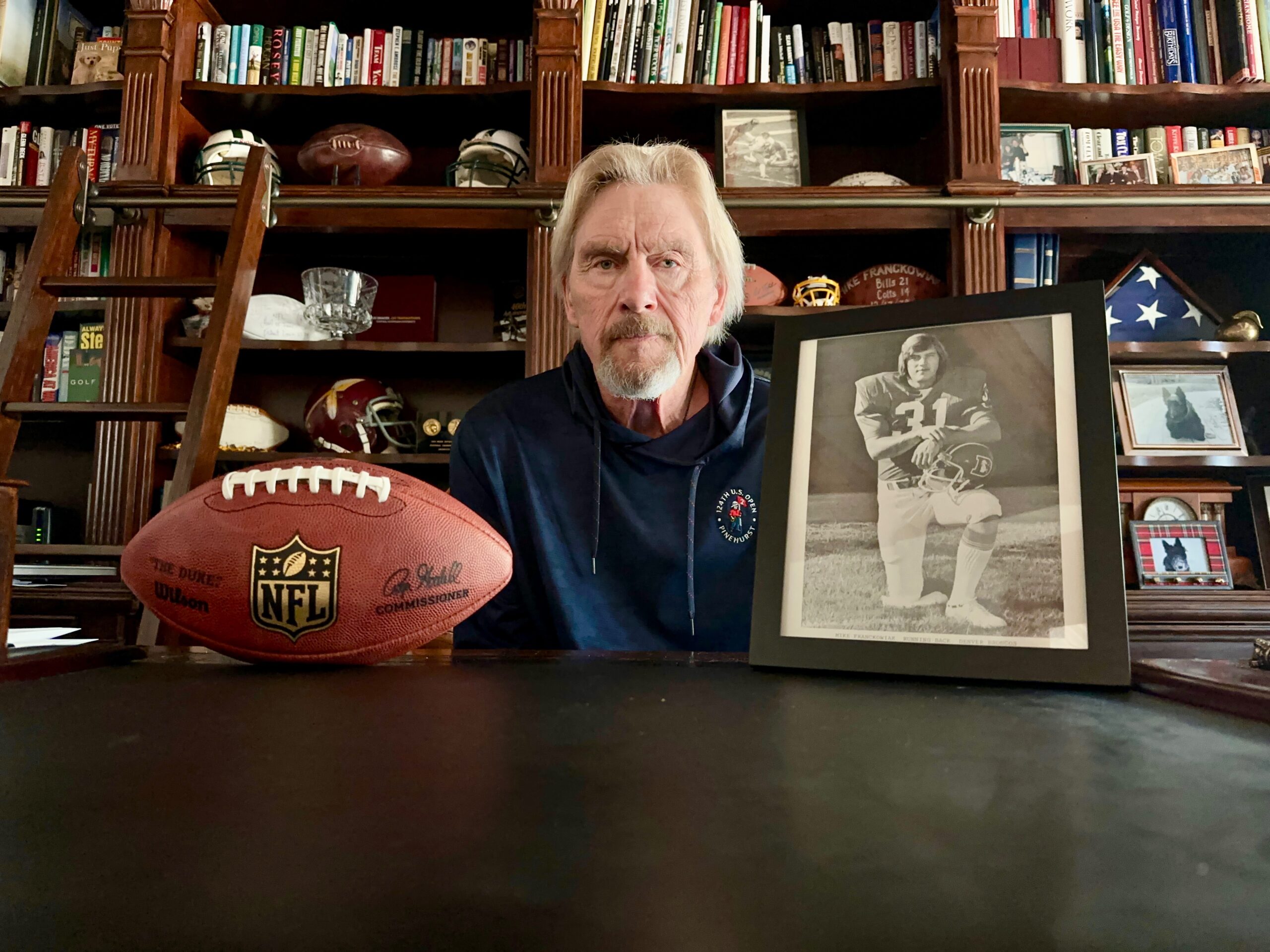 Mike Franckowiak, a fullback taken in the third round by the Denver Broncos in the 1975 NFL draft, at his home in Pinehurst, N.C., in March 2025 alongside a photo from his rookie year. Franckowiak, played four years in the NFL, his first two with the Broncos, before becoming a successful Wall Street stockbroker. He and his wife Gay Ebers-Franckowiak, who also worked on Wall Street, have donated more than $1 million to their alma mater Central Michigan. (Photo courtesy of Mike Franckowiak.) (Courtesy Mike Franckowiak)