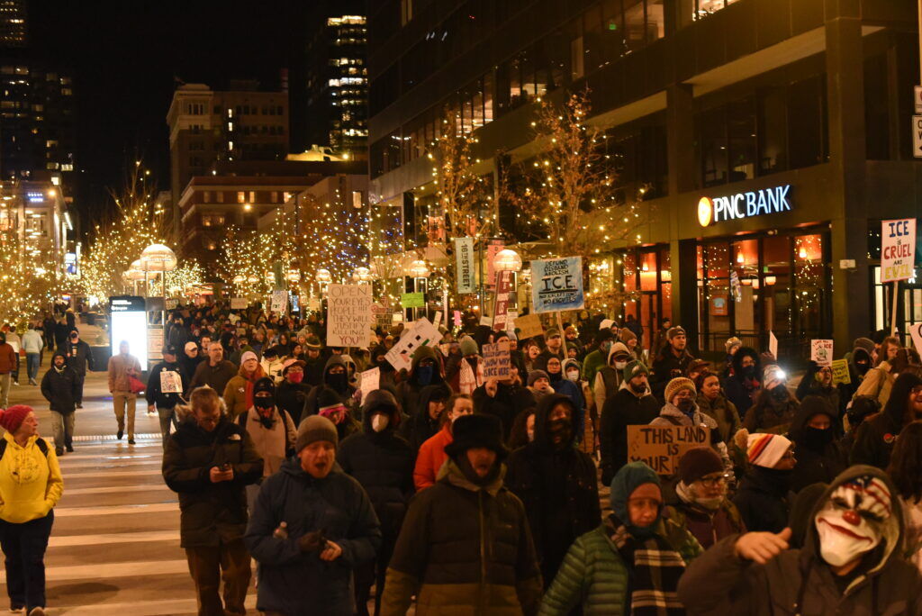 A large group of people marching down a street lined by string lights