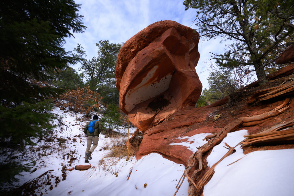 A hiker navigates around a balanced rock while hiking off the main loop trail in Red Canyon Park just outside Canon City, Colorado January 28, 2026. Photo by Mark Reis