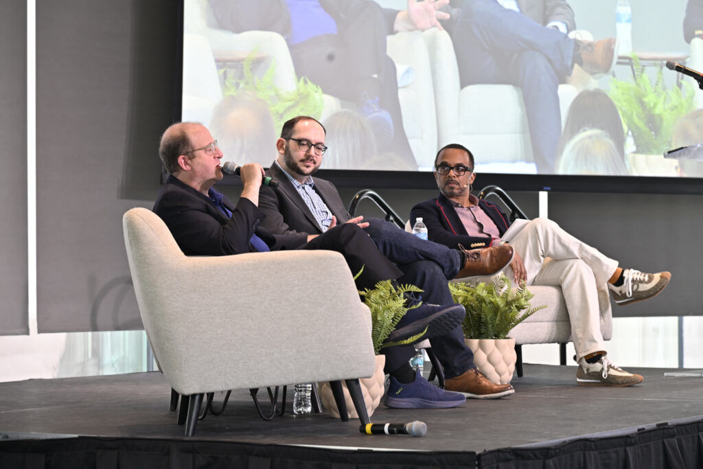 three men sitting in chairs on a stage