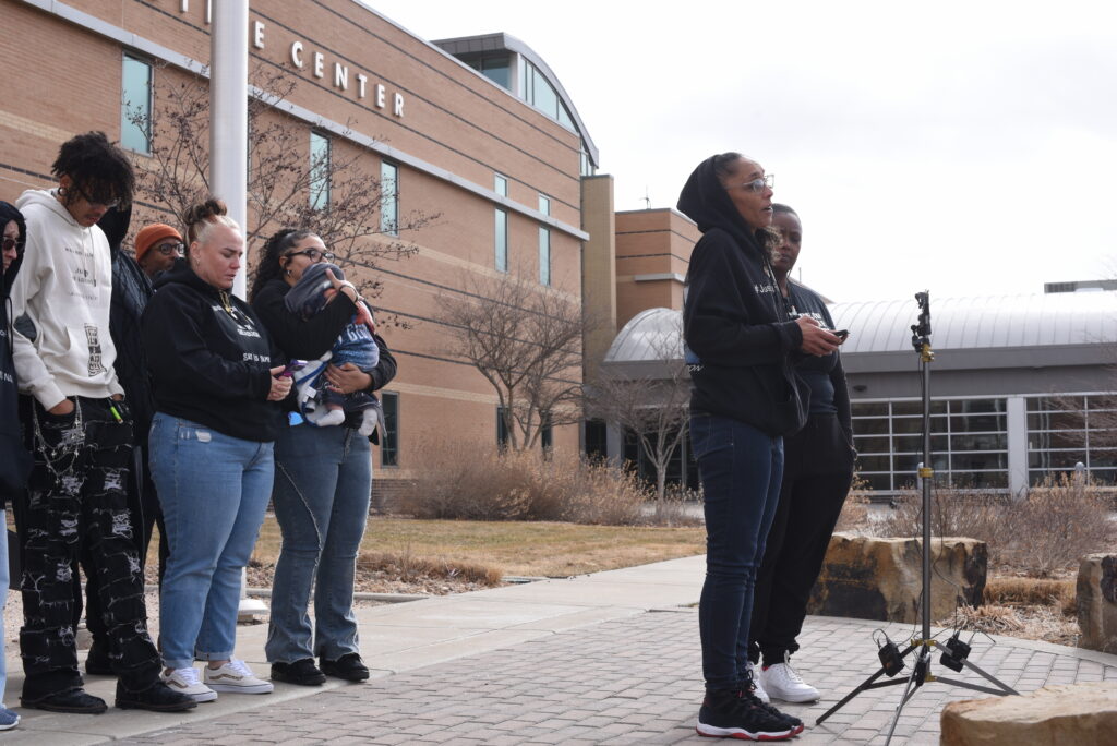 A woman stands at a microphone in front of a group of people