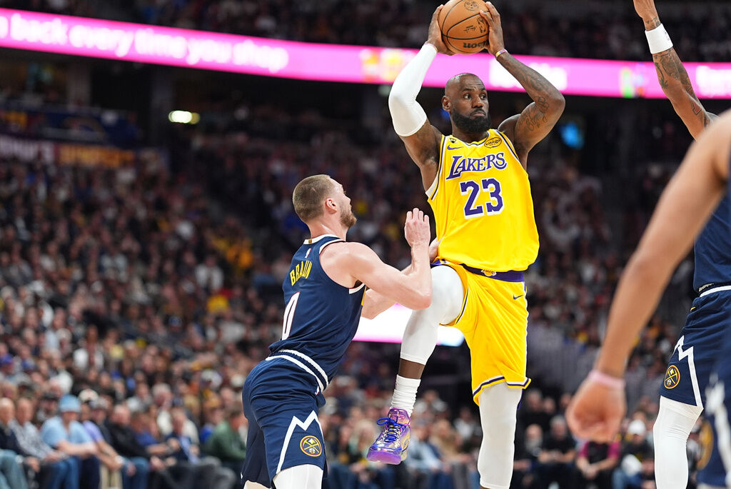 Los Angeles Lakers forward LeBron James, right, passes the ball as Denver Nuggets guard Christian Braun defends in the first half of an NBA basketball game, Thursday, March 5, 2026, in Denver.