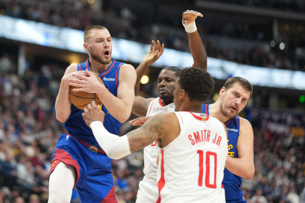 Denver Nuggets guard Christian Braun, left, pulls in a rebound as Houston Rockets forward Jabari Smith Jr., right, defends while center Clint Capela, back left, jostles for position with Denver center Nikola Jokić in the second half of an NBA basketball game Wednesday, March 11, 2026, in Denver.