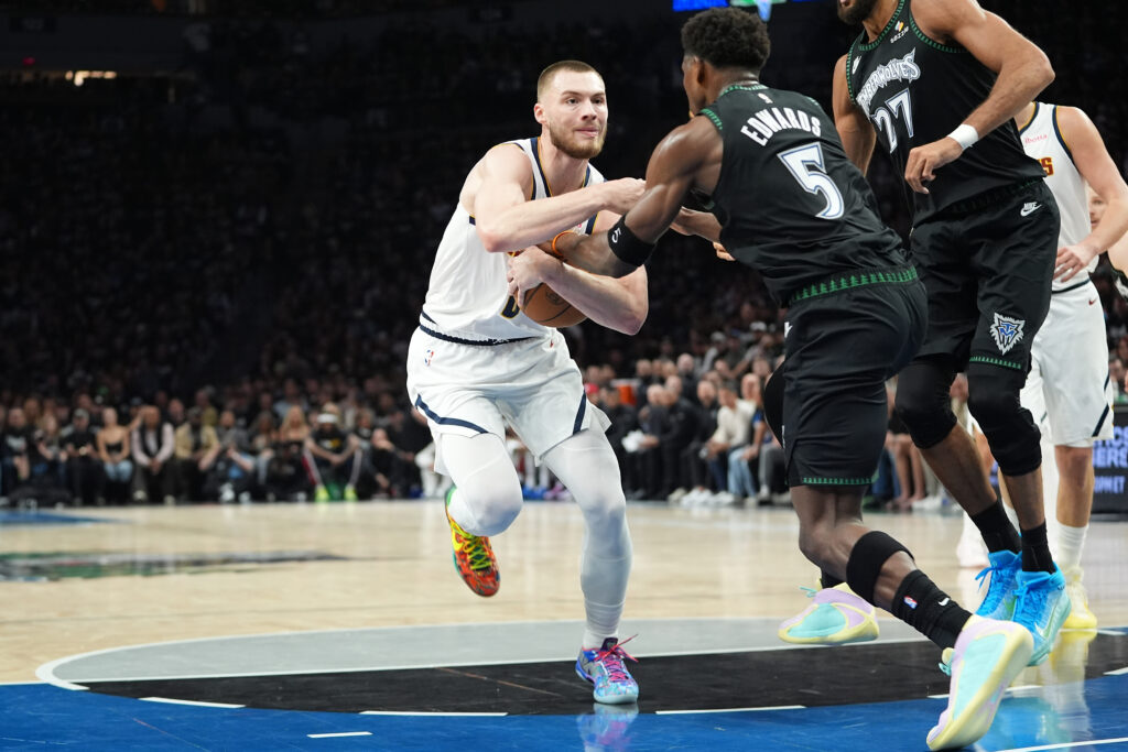 Denver Nuggets guard Christian Braun (0), left, works toward the basket as Minnesota Timberwolves guard Anthony Edwards (5) defends during the first half in Game 3 of a first-round NBA basketball playoff series, Thursday, April 23, 2026, in Minneapolis. (AP Photo/Abbie Parr)