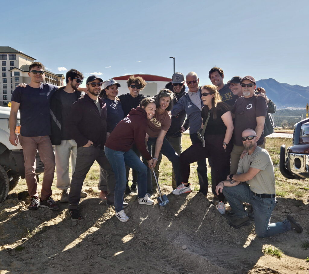 A group of CityROCK staff are all smiles as they collectively break ground on their second location, a new facility that will be built in northern Colorado Springs.