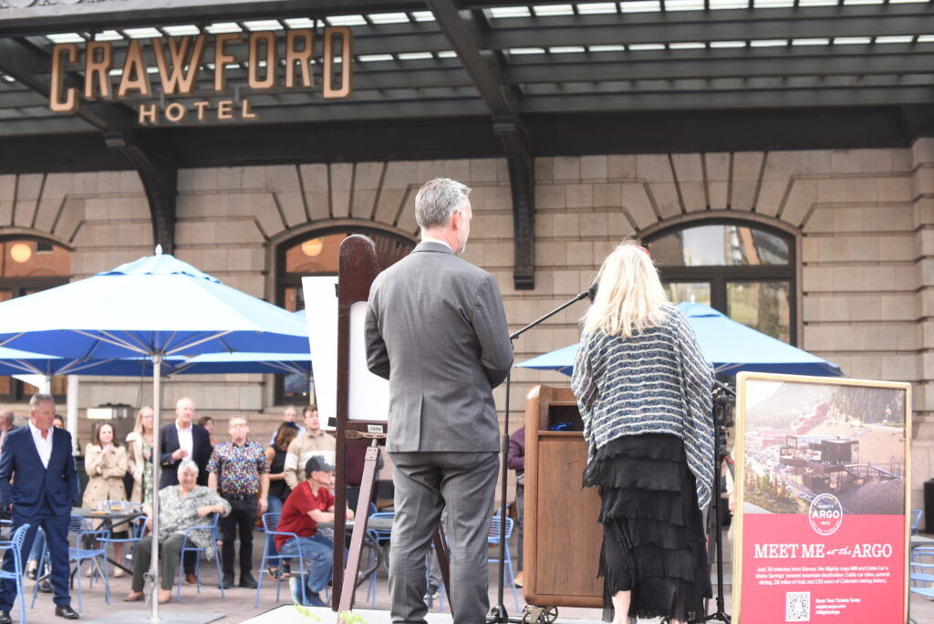Two people stand at a podium in front of a crowd