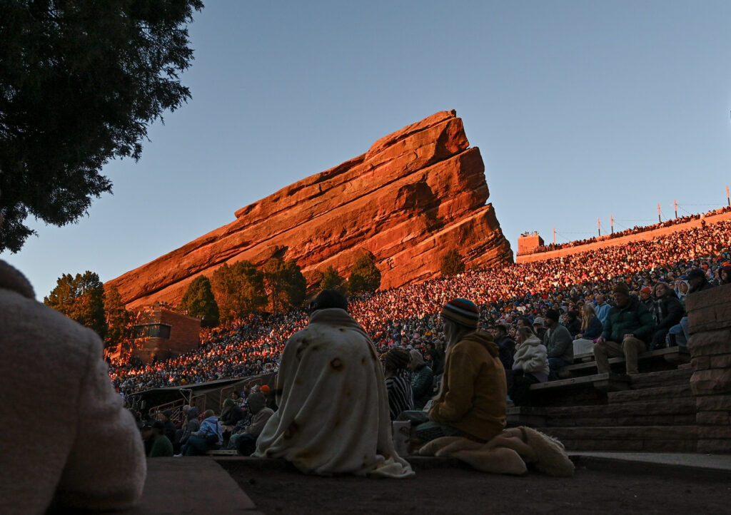 Sunrise hits red rocks while a crowd sits