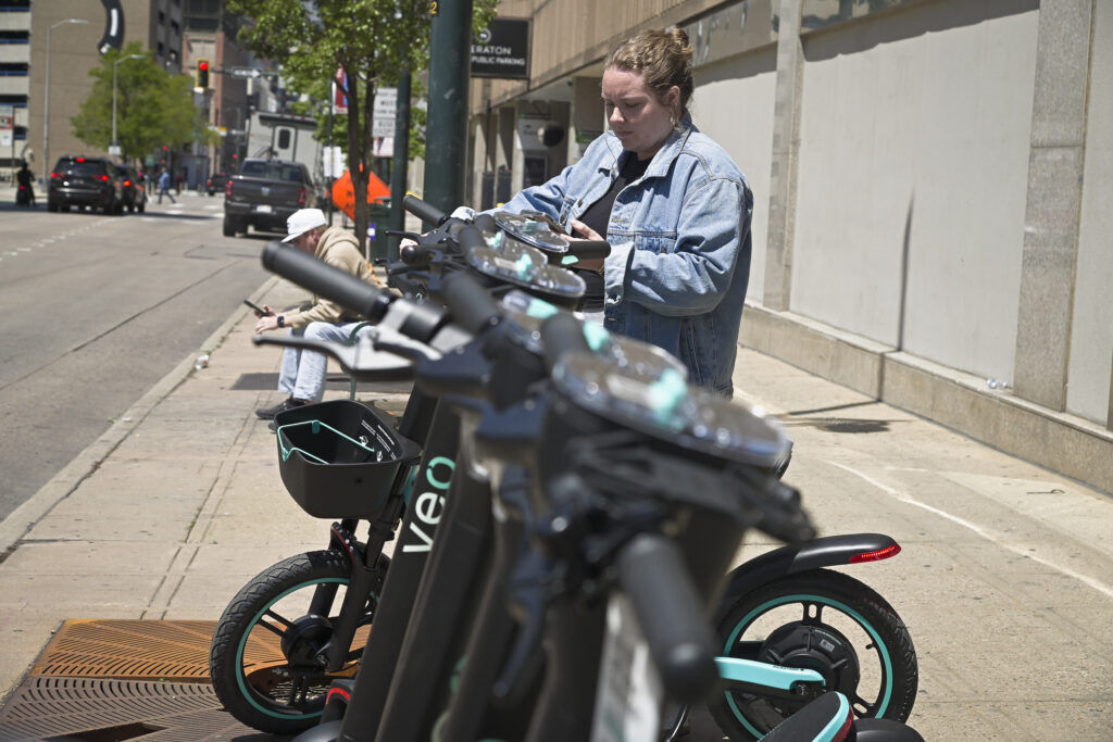 a woman uses an app to electronically unlock an electric scooter