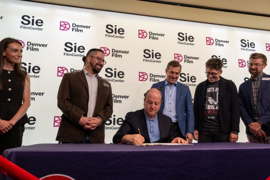 Gov. Jared Polis signs the artist-corporation bill, or A-Corp, into law at the Sie Film Center on June 2, 2026. (Provided by Ally Sullivan)