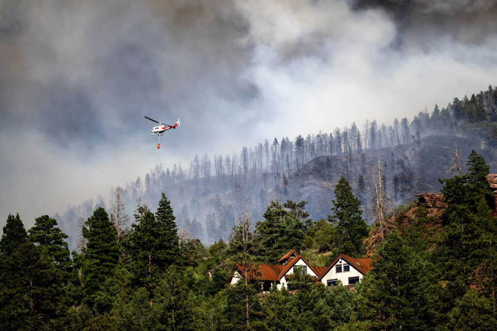 A helicopter provides bucket drops to assist firefighters battling the Gold Mountain Fire