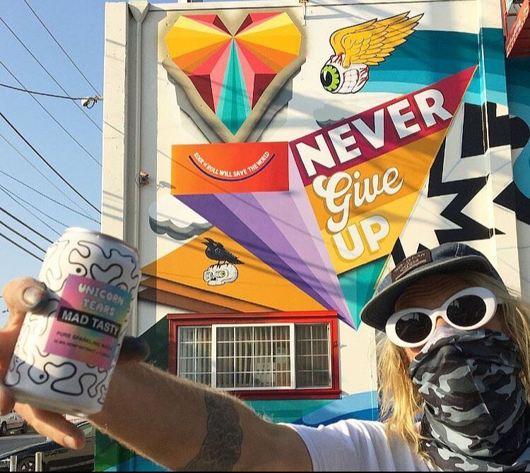 Artist Pat Milbery poses with one of his murals, which reads, "Never Give Up."