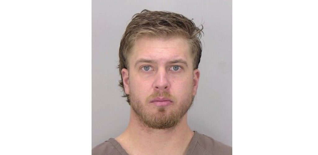 A mugshot of a man against a grey background