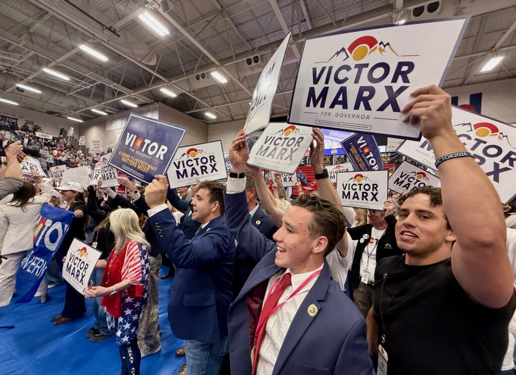 Supporters of Republican gubernatorial candidate Victor Marx wave signs as he takes the stage at the Colorado GOP's state assembly on Saturday, April 11, 2026, at Massari Arena on the Colorado State University Pueblo campus in Pueblo. (Ernest Luning/Colorado Politics)