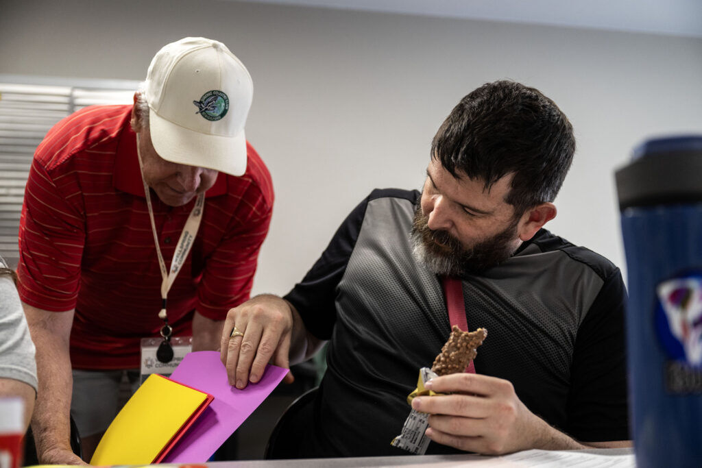 Nate picks a sheet of colored paper from a volunteer as he works on a scrapbook in a class at Wellspring in Castle Rock on Thursday, June 4, 2026. The Wellspring Community aims to help adults with intellectual and developmental disabilities live more satisfying, independent lives.